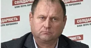 Чоловік у темному костюмі на тлі банера Солідарність Блок Петра Порошенка