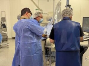 Лікарі в синіх халатах і масках працюють біля обладнання в операційній