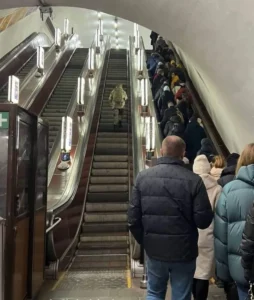 Солдат у камуфляжі сам піднімається ескалатором метро, поруч черга цивільних