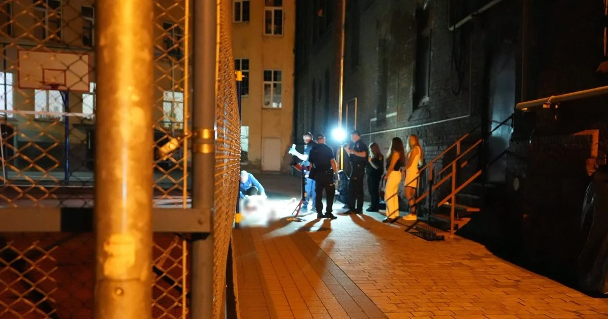 Поліцейські та люди біля лежачої фігури на нічному подвір’ї зі сіткою