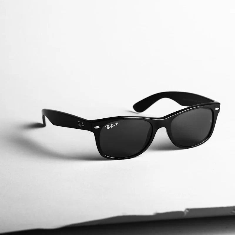 Чорні сонцезахисні окуляри Ray-Ban Wayfarer з темними лінзами на білій поверхні