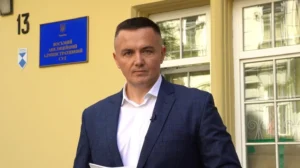 Чоловік у синьому костюмі з паперами біля вивіски Восьмого апеляційного адміністративного суду