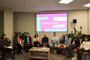 Учасники панельної дискусії сидять перед екраном із презентацією на книжковому форумі