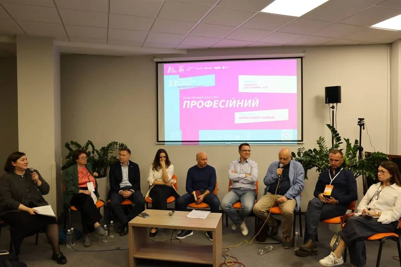 Учасники панельної дискусії сидять перед екраном із презентацією на книжковому форумі