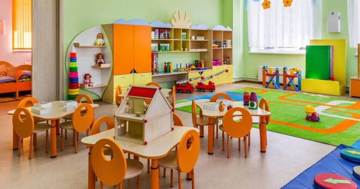 Ігрова кімната дитсадка з помаранчевими столами, стільцями та іграшками