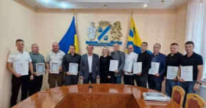 Група людей з грамотами біля герба Стрийського району в залі адміністрації