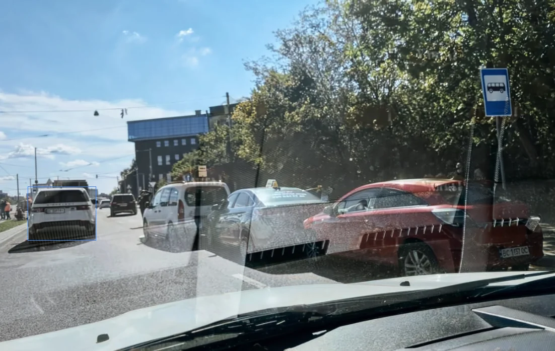 Вид крізь лобове скло на дорогу з кількома авто та знаком зупинки