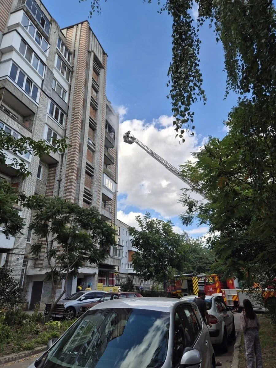 Пожежна машина з висунутою драбиною біля багатоповерхівки з якої йде дим у Києві